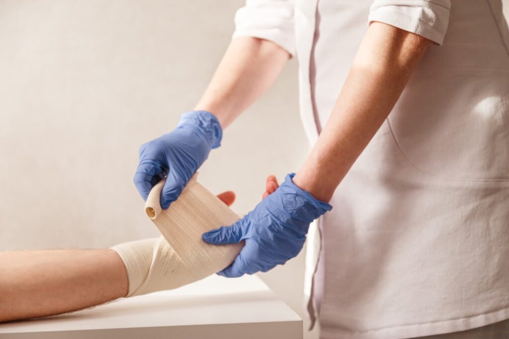 auxílio acidente - enfermeiro enfaixando a mão de um paciente